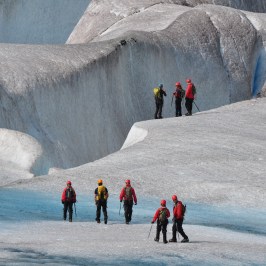 a group of people walking in front of a large rock