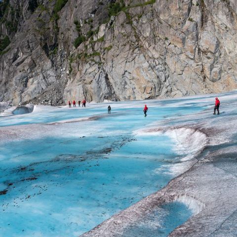a group of people swimming in the water with a mountain in the background