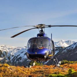 a helicopter flying over a snow covered mountain